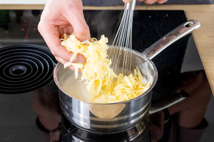 geriebenen Käse in den Topf geben