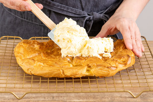 Buttercreme auf dem Brandteig der Karpatka verstreichen