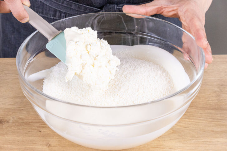 Schlagsahne zur Kokoscreme des Kokos-Käsekuchens geben