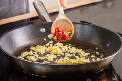 Tomatenmark in die Pfanne geben