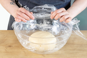 Schüssel mit Teig mit Frischhaltefolie abdecken