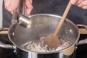 Zwiebelwürfel und Knoblauch in den Topf geben