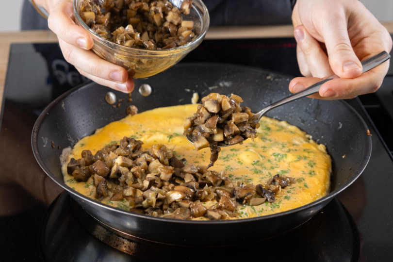 Pilze auf Omelett verteilen