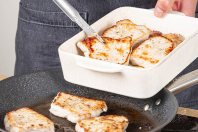 Schnitzel aus der Pfanne in eine Auflaufform legen
