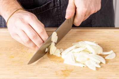 Knoblauch in Scheiben und Zwiebel in Strefen schneiden