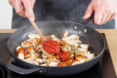 Gewürze und Paprikamark zum Hähnchen geben