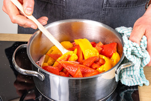 Paprikas und Tomaten in Topf geben