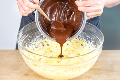 geschmolzene Kuvertüre unter Butter-Eigelb-Masse rühren