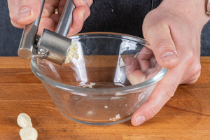 Knoblauch in eine Schüssel pressen