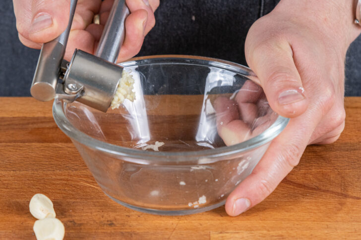 Knoblauch in eine Schüssel pressen