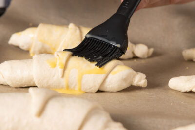 Die Croissants mit Eigelb-Milch-Gemisch bestreichen