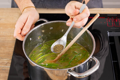 Würzige Schnibbelbohnensuppe mit Bohnenkraut, Salz und Pfeffer würzen
