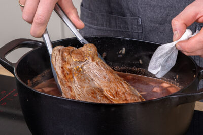Schweinebraten samt Gewürzbeutel in den Bräter geben