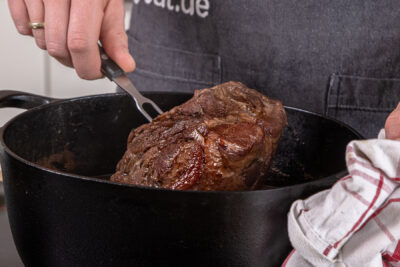 Schweinebraten aus dem Bräter nehmen