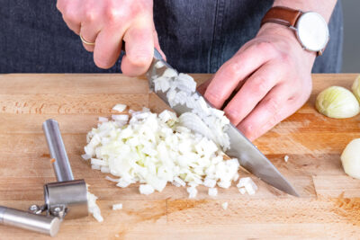 Knoblauch pressen und Zwiebeln würfeln
