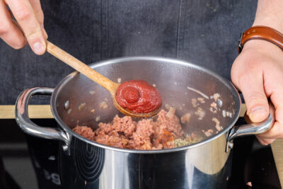 Tomatenmark in den Topf geben