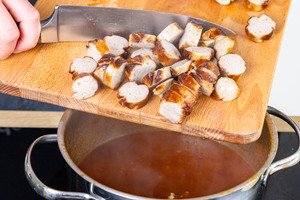 Bratwürste in die Curry-Sauce geben