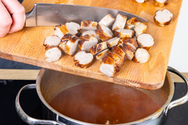 Bratwürste in die Curry-Sauce geben