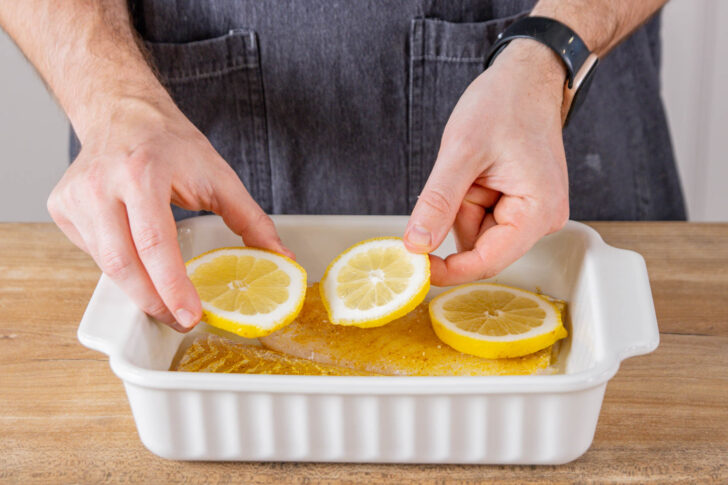 Zitronenscheiben auf Fischfilet platzieren