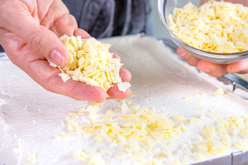 Frau-Holle-Kuchen mit weißer Raspelschokolade bestreuen