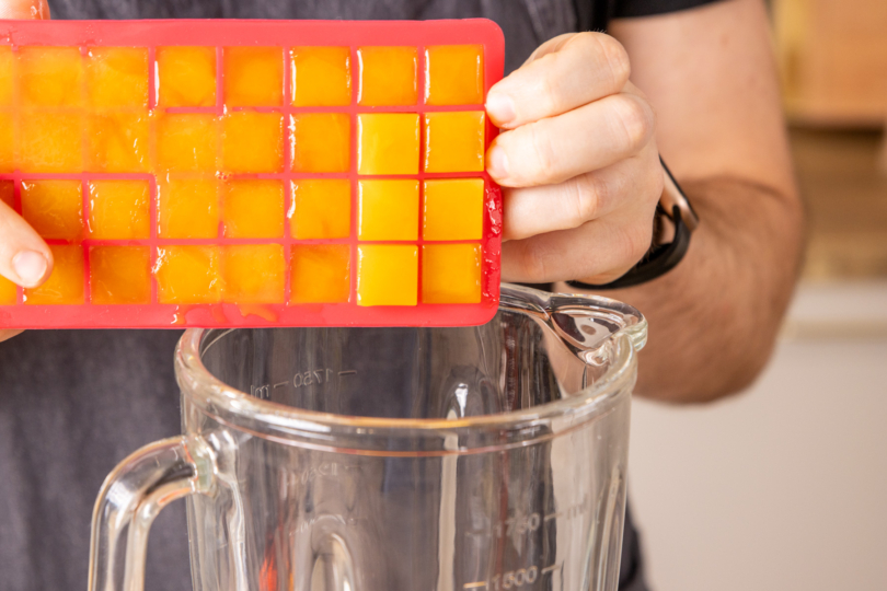 Orangensaft-Eiswürfel in Mixer geben