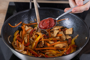 Tomatenmark in den Wok geben