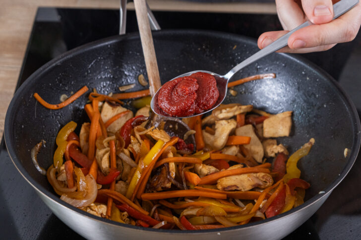 Tomatenmark in den Wok geben