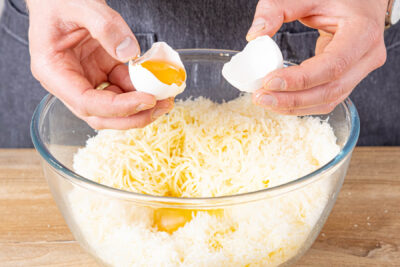 Eier, Mehl und Backpulver zum Käse geben