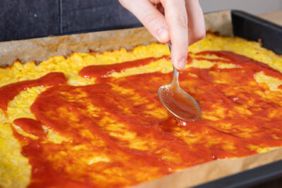 Kartoffelpizza mit passierten Tomaten bestreichen