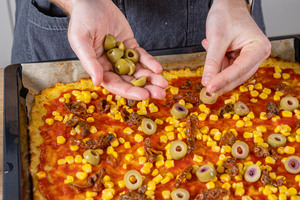 Kartoffelpizza mit Oliven belegen
