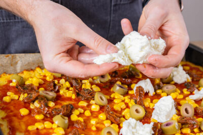 Mozzarella über Kartoffelpizza zupfen