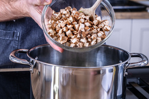 Champignons in den Topf geben