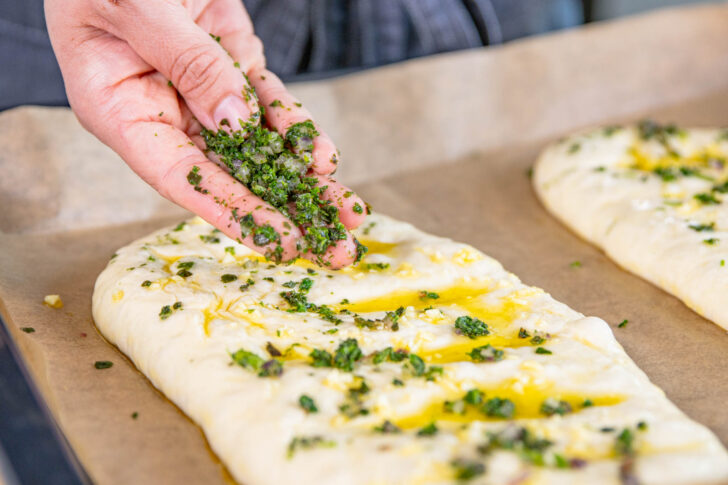 Pizzabrote mit Knoblauchöl besteichen und mit Kräutern bestreuen