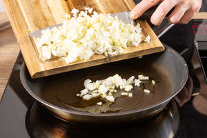 Zwiebel- und Knoblauchwürfel in die Pfanne geben