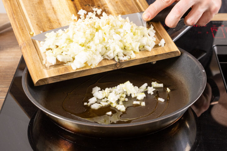 Zwiebel- und Knoblauchwürfel in die Pfanne geben