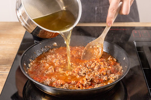 Gemüsebrühe zum Hackfleisch gießen