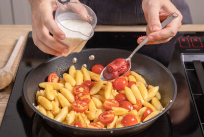 Cremefine und Tomatenmark in Schupfnudelpfanne unterrühren