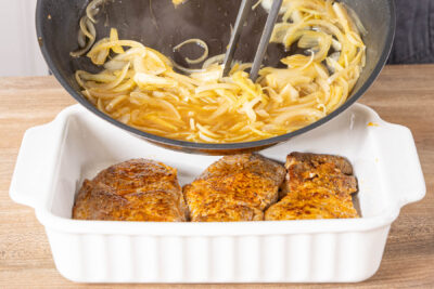 Zwiebel über das gebratenen Fleisch geben und im Ofen garen
