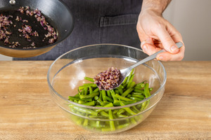 Zwiebeln in den Brechbohnensalat geben