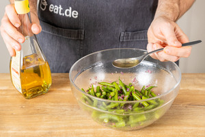 Einen Löffel Essig in den Brechbohnensalat geben