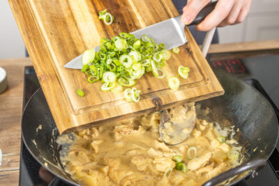 Frühlingszwiebeln zu Hähnchencurry mit Ananas dazugeben