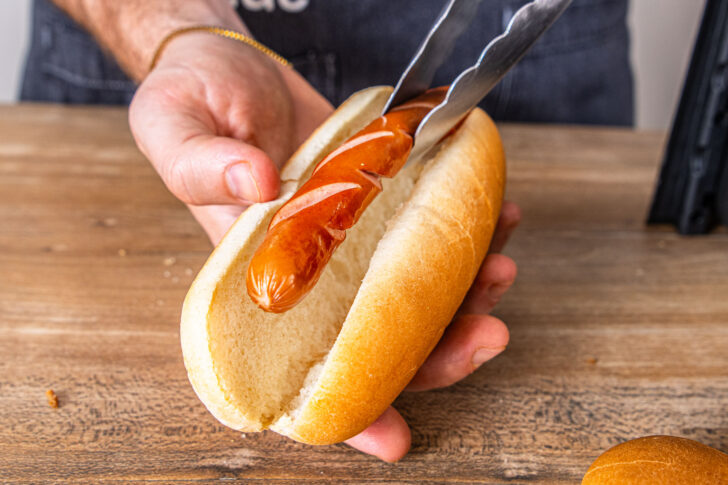 Wurst in das Brötchen geben