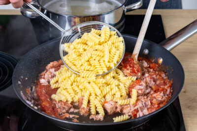 gekochte Pasta mit Sauce vermengen