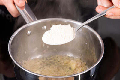 Zwiebeln und Knoblauch anbraten, Mehl unterrühren
