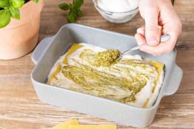 Pesto Genovese auf der Béchamelsoße verstreichen