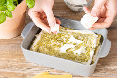 Pesto-Lasagne zuletzte mit Béchamelsoße und Mozzarella belegen
