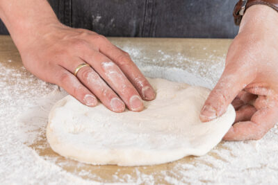 Den Teig dehnen und zu einer Pizza formen