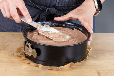 Schokocreme auf dem Keksboden des schnellen Kuchens ohne Backen verteilen