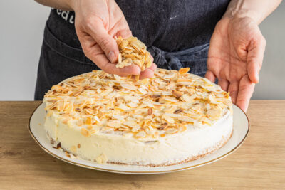 fertige vegane Mandeltorte mit gehobelten Mandeln dekorieren