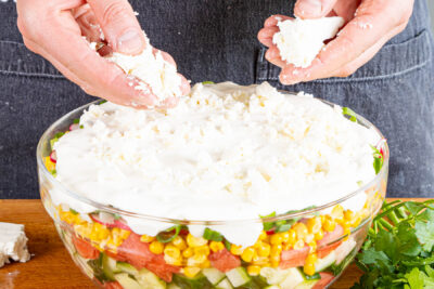 Sommer-Schichtsalat mit Feta garnieren